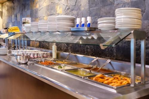 a buffet line with plates and food in a restaurant at Quality Inn Mazatlan in Mazatlán