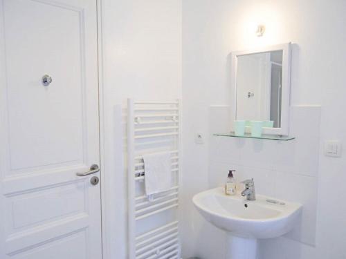 Baño blanco con lavabo y espejo en Gite Le Chevalier en Gavray