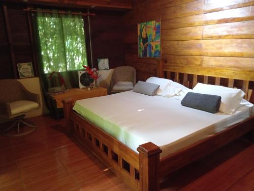 1 dormitorio con 1 cama grande en una habitación con paredes de madera en Finca La Paz, en Puerto Viejo