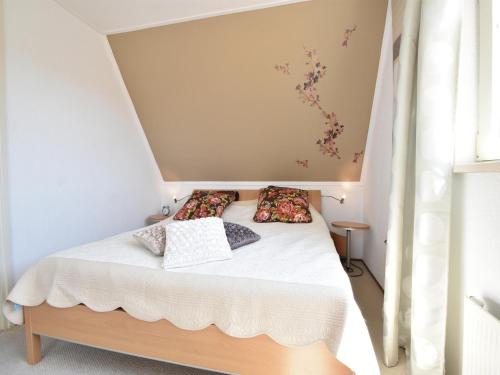 een kleine slaapkamer met een bed met witte lakens en kussens bij Villa Robinie in Oude-Tonge