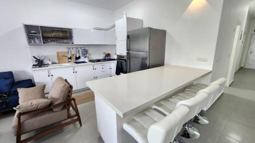 a kitchen with a white counter and chairs in it at Haifa night's in Haifa
