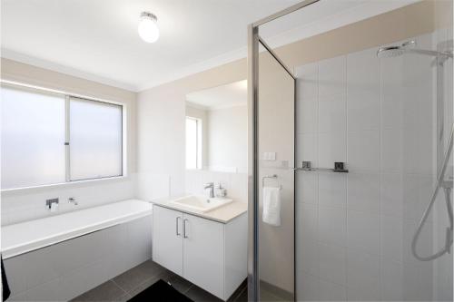 a white bathroom with a sink and a shower at Shoalhaven Escape Cowes in Cowes