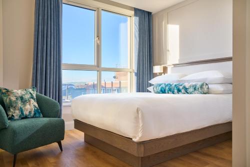 um quarto com uma cama grande, uma cadeira e uma janela em The James Hotel em Tralee