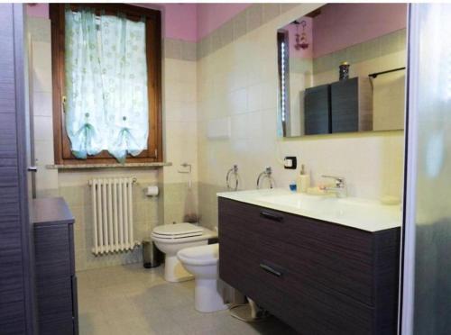 a bathroom with a sink and a toilet and a window at La casa dell'ulivo in Brembate