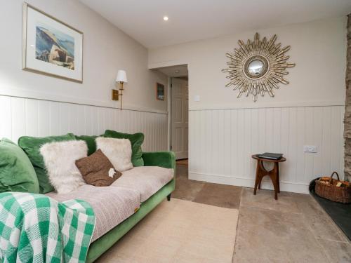 a living room with a green couch and a mirror at Gosling Cottage in Kendal