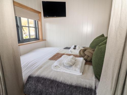 a bedroom with a bed with towels and a television at Shepherd Hut 2 in Harrogate