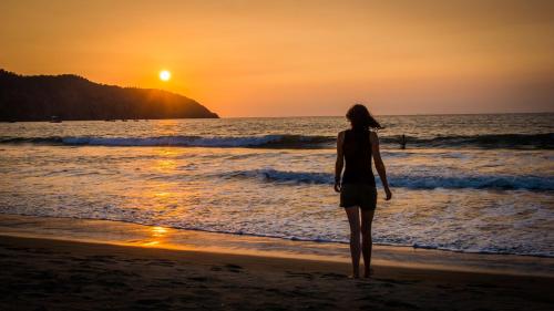 a woman standing on the beach watching the sunset at Victor Hugo Hotel in Puerto López