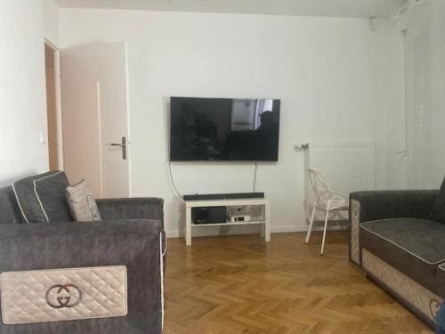 un salon avec deux canapés et une télévision à écran plat dans l'établissement Appartement cosy et lumineux 3 pieces, à Drancy