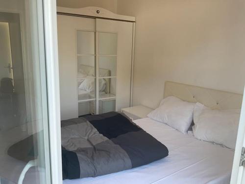 une chambre avec un lit blanc avec un miroir dans l'établissement Appartement cosy et lumineux 3 pieces, à Drancy