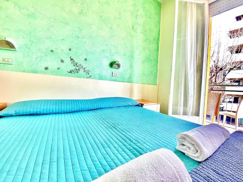 a bedroom with a blue bed and a window at Hotel Majorca Nuova Gestione Rimini 100 m dalla spiaggia in Rimini