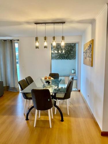 a dining room with a glass table and chairs at Green&Blue in Ribeira Grande