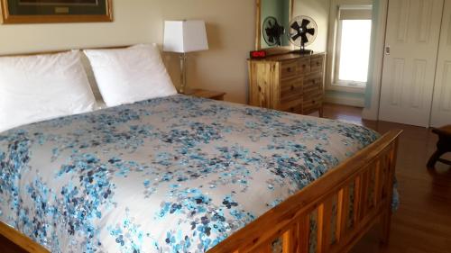 een slaapkamer met een bed met blauwe bloemen erop bij Casa Loma BnB in West Kelowna