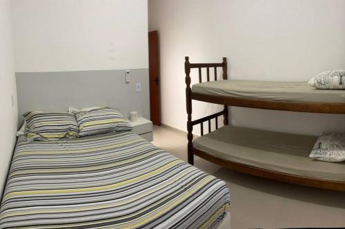 ein Schlafzimmer mit einem Bett und einem Etagenbett in der Unterkunft Casa com piscina ACONCHEGO no balneário de Shangri-lá in Pontal do Paraná