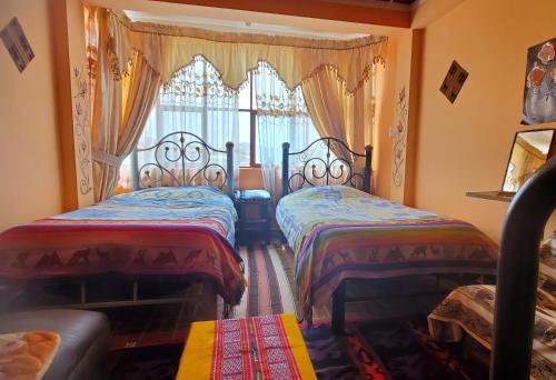 twee bedden in een kamer met een raam bij Hostal Golden Quinua in Uyuni