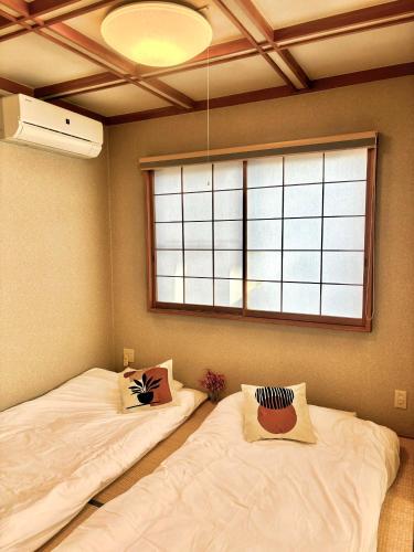 two beds in a room with a window at Koiwa Detached house 小岩駅にある戸建のおうち in Tokyo