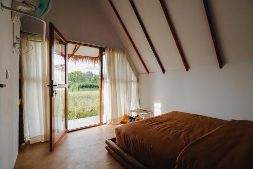 a bedroom with a bed and a large window at BAMBOO SHACK in Bukittinggi