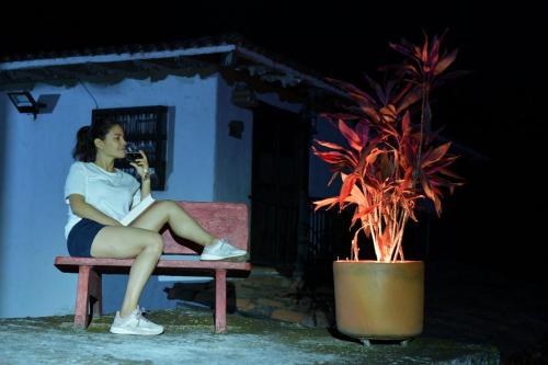 a woman sitting on a bench next to a potted plant at La Villa The View in Pance