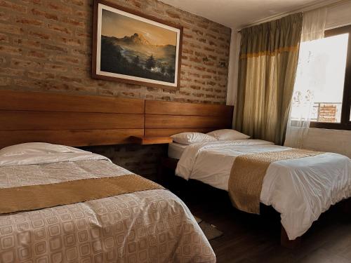 a hotel room with two beds and a brick wall at Mercedes Restaurant B&B in Baños