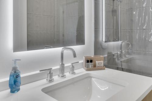 un lavabo con espejo y una botella de jabón. en Fully Furnished Apartment in Washington near Logan Circle en Washington
