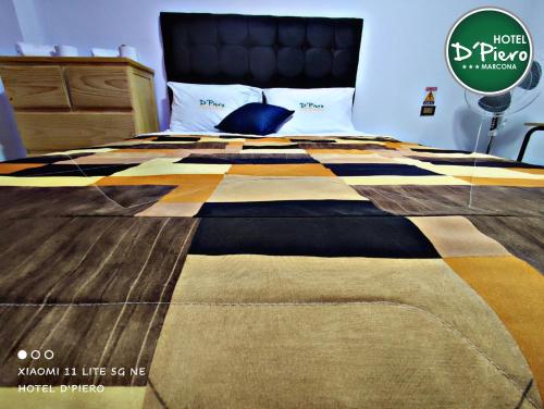 a bed with a checkered blanket on top of it at HOTEL D'PIERO MARCONA in San Juan de Marcona