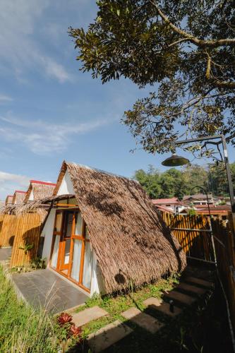 a small house with a thatched roof and a fence at BAMBOO SHACK in Bukittinggi