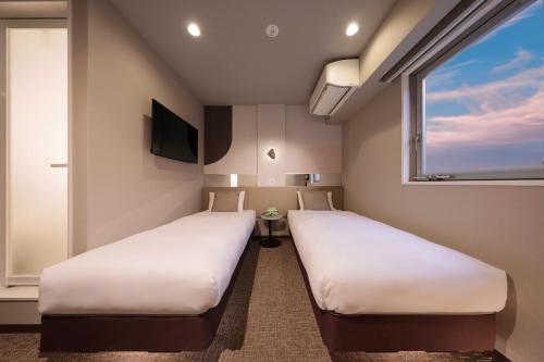 two beds in a room with a window at Tennouji Crystal Hotel in Osaka