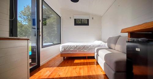 - un petit salon avec un canapé et une fenêtre dans l'établissement CheTiny Sunset - Tiny House en Sierra de los Padres, à Sierra de los Padres