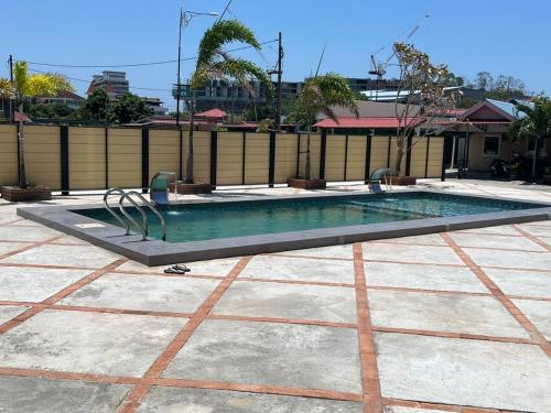 a swimming pool in a yard with a fence at Dhania Cenang Beach Motel in Pantai Cenang
