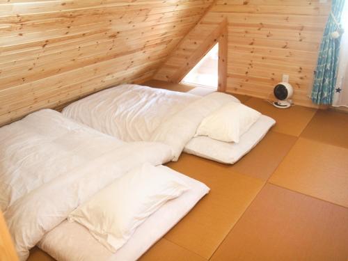 two beds in a room with wooden walls and a window at 島ログ in Miyako Island