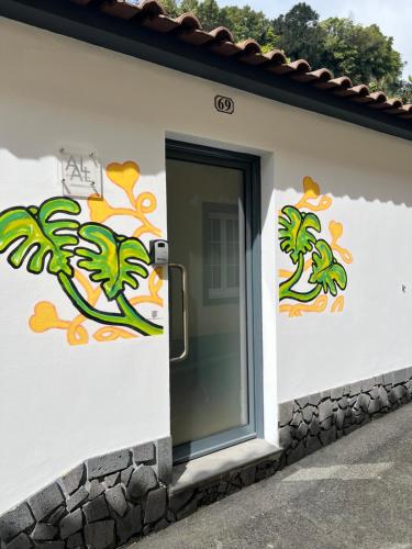 a white building with a door with flowers on it at Casa da Cascata do Segredo in Vila Franca do Campo