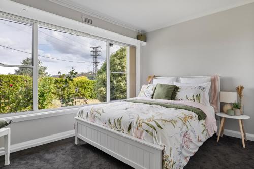 een slaapkamer met een bed en een groot raam bij Legana Lodge - Your home away from home - Catering for up to 12 guests in Legana