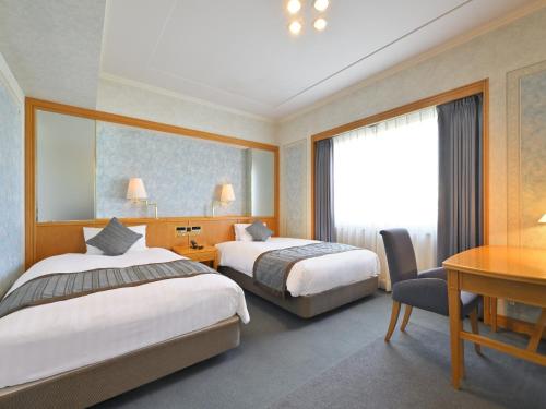 a hotel room with two beds and a desk at Takamatsu Kokusai Hotel in Takamatsu