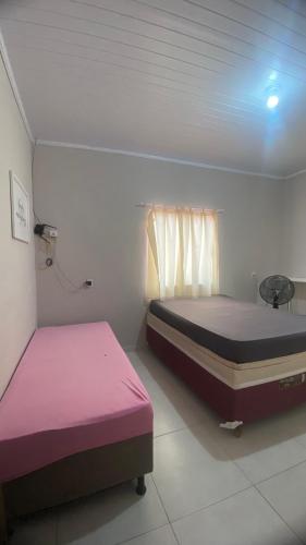 - 2 lits dans une petite chambre avec des draps roses dans l'établissement Casa Azul do Capão, à Palmeiras