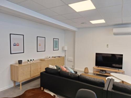 a living room with a couch and a flat screen tv at Huis ALNA 5 in Mechelen