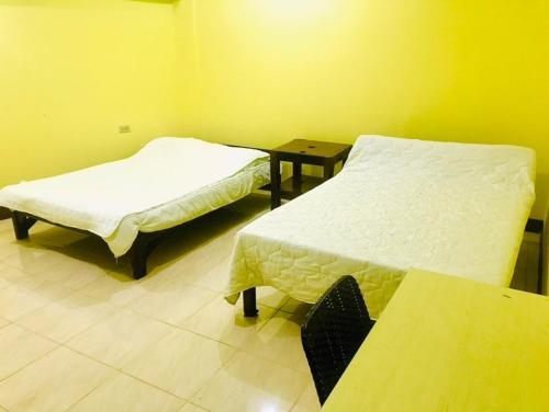 a room with two beds and a table in it at RAYAS Guesthouse- No Credit Card Needed in Baguio