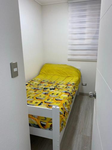 a small bedroom with a bed with a yellow comforter at Hermoso departamento Tabo Playa Paraiso in El Tabo