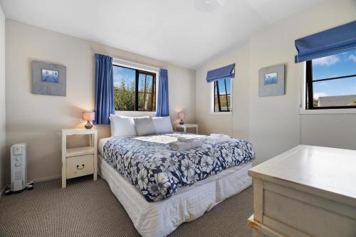 a bedroom with a bed and two windows at Maytime Cottage - Arrowtown Holiday Home in Arrowtown