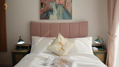 um quarto com uma cama branca e uma cabeceira rosa em Executive 1BR apartment em Abu Dhabi