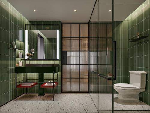 a bathroom with a toilet and green tiles at Citadines Connect East Chengdu in Xinsanchaba