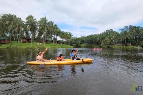 a woman and two children on a yellow kayak in the water at Caliraya Ecoville Recreation and Farm Resort in Cavinti