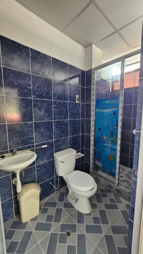 La salle de bains est pourvue de carrelage bleu, de toilettes et d'un lavabo. dans l'établissement Casa Verde, à Quillabamba