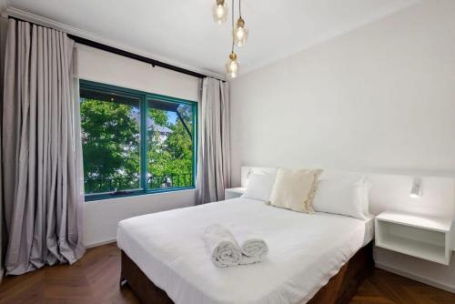 a bedroom with a large white bed with a window at Warmful Apt in Subiaco w Free Parking in Perth