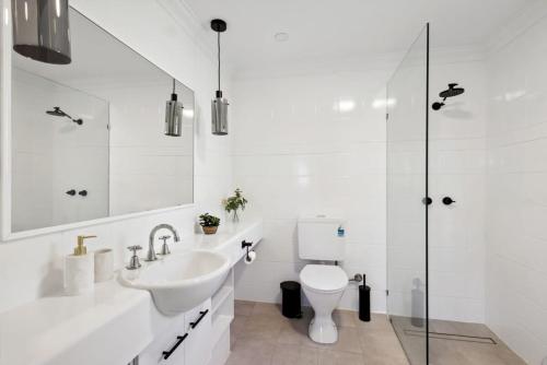 a white bathroom with a sink and a toilet at Warmful Apt in Subiaco w Free Parking in Perth