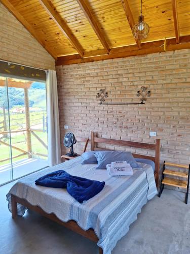 a bed in a room with a brick wall at Chalés de Hórus in São Thomé das Letras