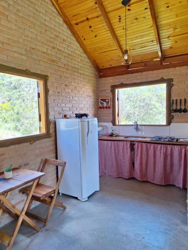a kitchen with a white refrigerator and a table at Chalés de Hórus in São Thomé das Letras