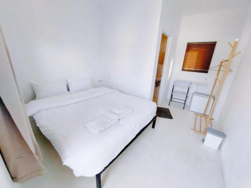 a white bedroom with a white bed and a chair at เบา ป่าตอง Bao Pathong Beach in Patong Beach