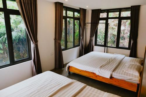 a bedroom with two beds and windows at DC Green Resort Bavi - Resort villa complex with private pool and Mountain view in Hanoi