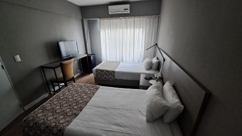 a hotel room with two beds and a television at Hotel 8 de Octubre in Buenos Aires