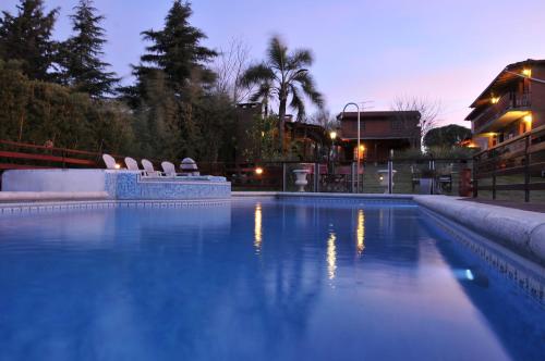 a swimming pool with chairs in a city at night at Cabañas Nueve Lunas in Villa Carlos Paz