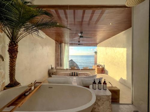 a large bath tub in a bathroom with a palm tree at Mahi Mahi Beach Shack And Suites in Uluwatu